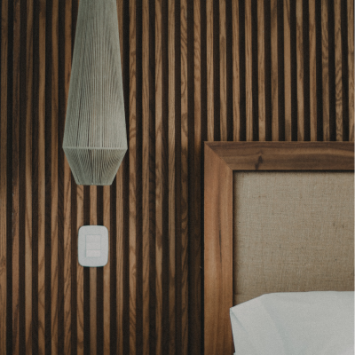 Wooden headboard and hanging pendant light in a modern Tulum bedroom.