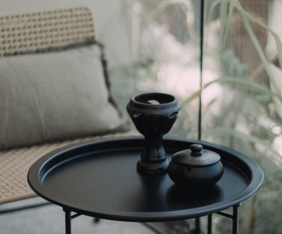 Black side table with ceramic decor in a modern Tulum home.