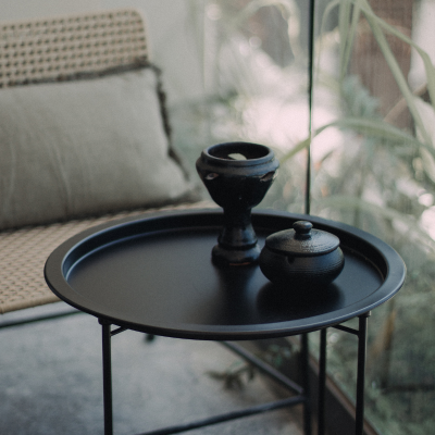 Black side table with ceramic decor in a modern Tulum home.